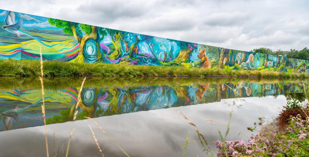 La fresque murale « La Forêt Enchantée » (du collectif d’artistes Treepack), située le long du canal à Lembeek, fait partie du projet « Zinderende Zenne » de la ville de Hal